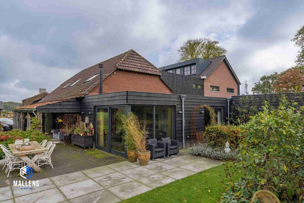 Eindresultaat van de ruime mantelzorgwoning. Je ziet de zwarte uitbouw met houten rabatdelen, en twee puien in de hoek.