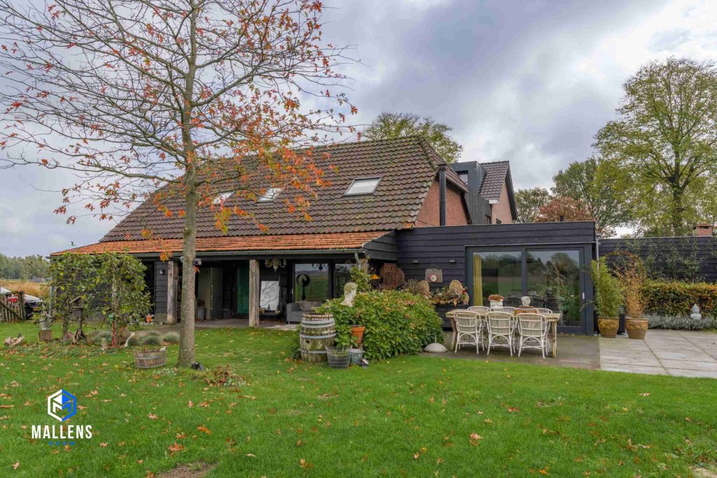 De ruime mantelzorgwoning in Biezenmortel met de zwarte uitbouw, gezien vanuit de achtertuin.