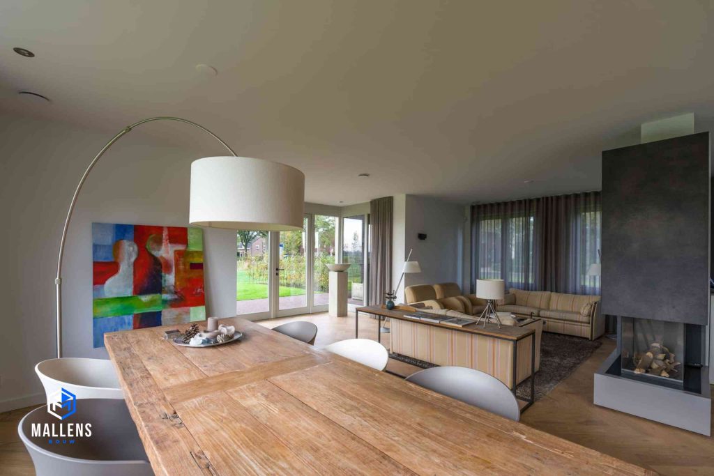 De eettafel met een gebogen staande lamp. Op de achtergrond zie je de zithoek.