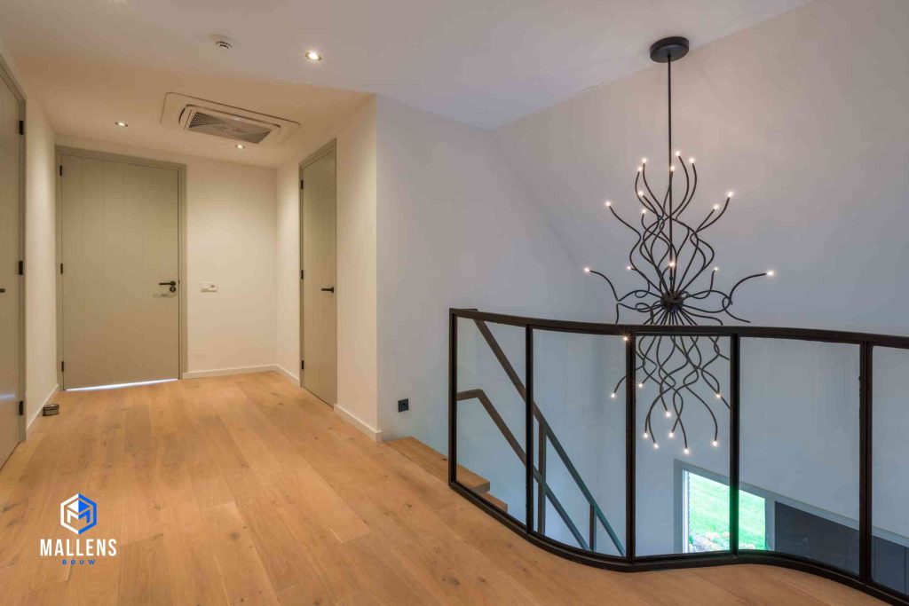 De overloop van de woning met een glazen reling omvat door zwarte staal.