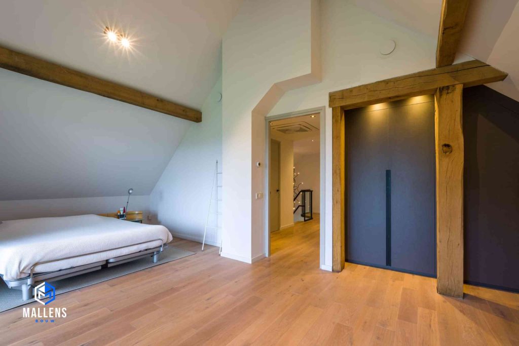 Een slaapkamer in de woonvilla in Biezenmortel. Er zijn houten balken in de ruimte verwerkt en er staat een tweepersoonsbed.