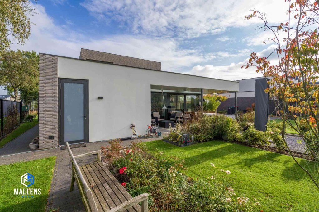 De achterzijde van de woning met een overkapping, met daaronder een zitje.