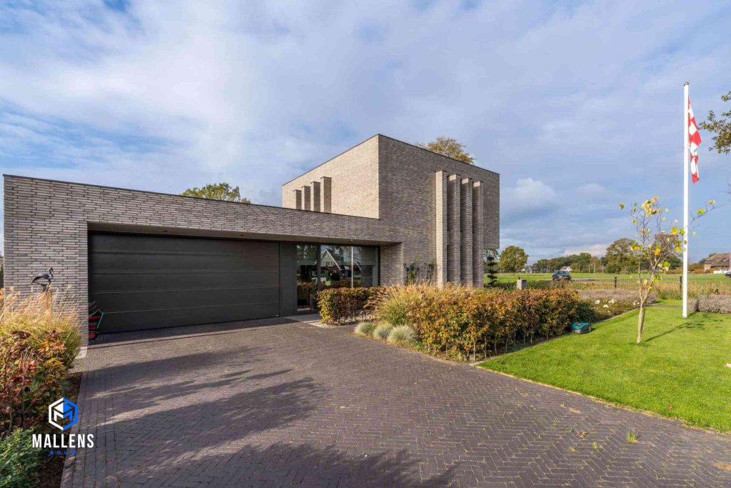 De woning van de schuin van voren gezien, met een grote garage.