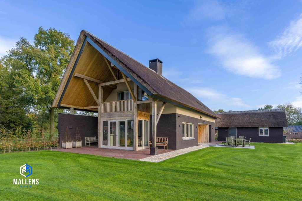 De woning van schuin voren bekeken. Ook hier zie je het uitstekende dak en de grote ramen en deuren.