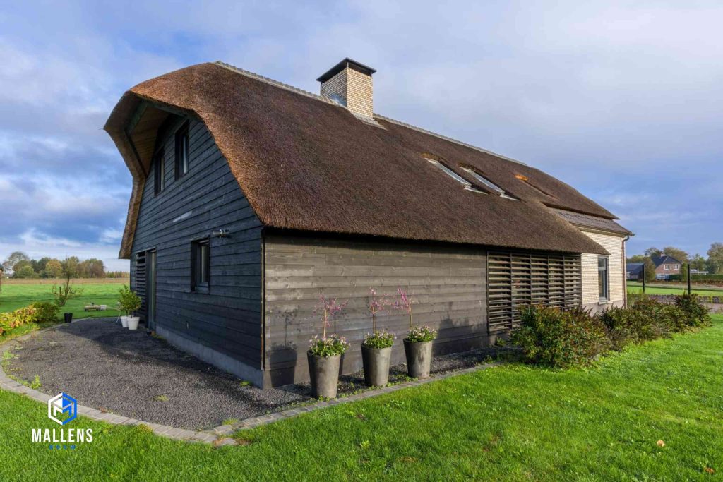 De woonboerderij in Biezenmortel van de achterzijde gezien met het rieten dak en houten afwerking.