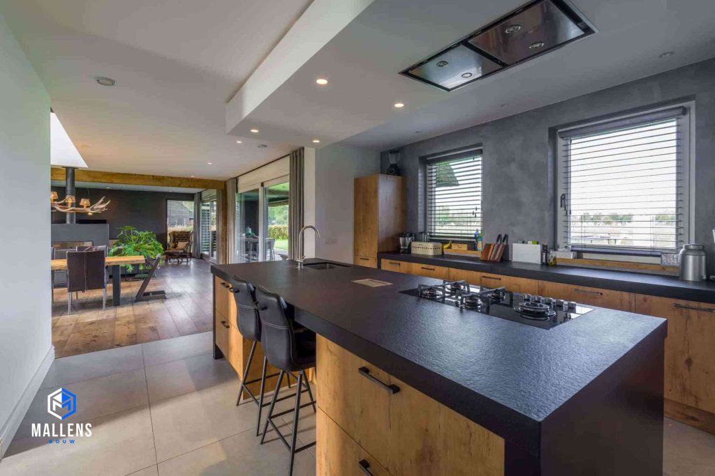De keuken met het keukenblok en twee barstoelen daaraan. Op de achtergrond zie je de eethoek.
