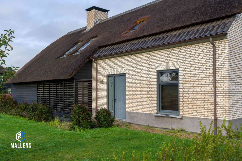 Een close-up van de woning waarin de scheiding tussen het houten gedeelte van de woning en het bakstenen gedeelte naar voren komt.