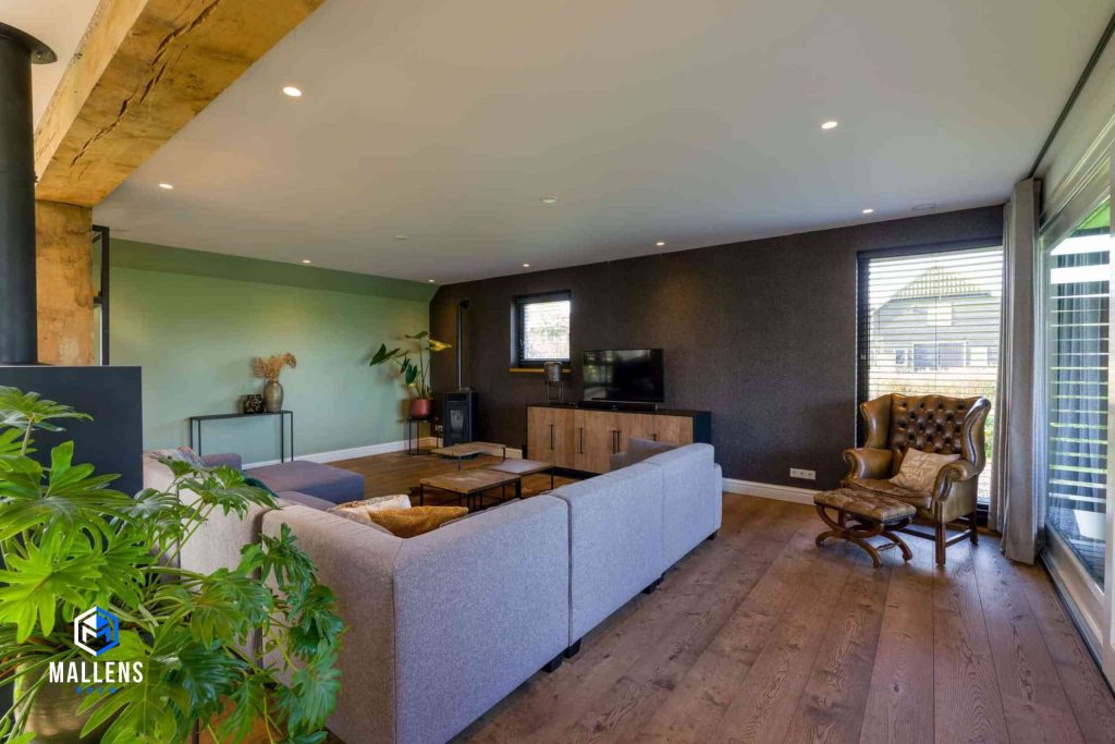 Het woongedeelte met een grijze gestoffeerde bank. In de hoek staat een leren loungestoel.