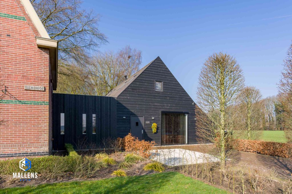Vooraanzicht van de Vlaamsche schuur Helvoirt, nu een woning, bestaande uit houten zwarte planken.