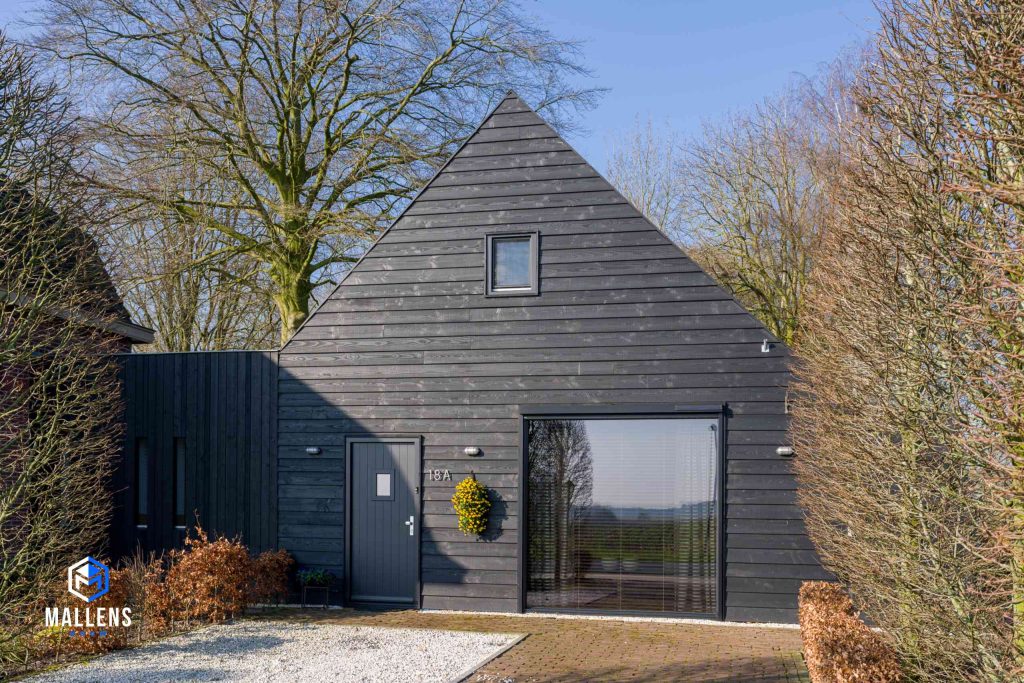 Het met zwarte planken bedekte vooraanzicht van de oude schuur in Helvoirt.