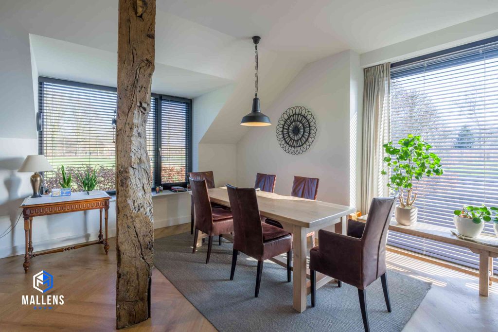 De eethoek met de eettafel en 5 eetstoelen. De houten balk staat naast de eettafel.