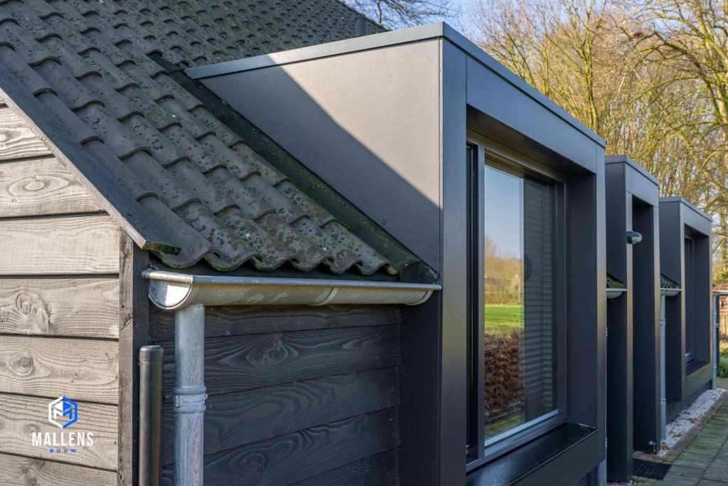 Detailfoto van de zijkant van de woning met het lage dak en de drie ramen.