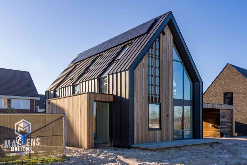 Het zijaanzicht van de nieuwbouwwoning Udenhout met op het hek ernaast het logo van Mallens Bouw.