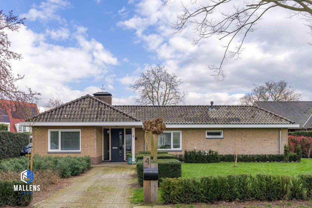 Je ziet de bungalow van voren met aan de straat de brievenbus en huisnummer.