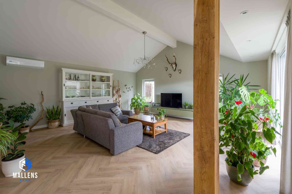 De woonkamer van de bungalow Moergestel met een stoffen grijze bank en diverse planten.