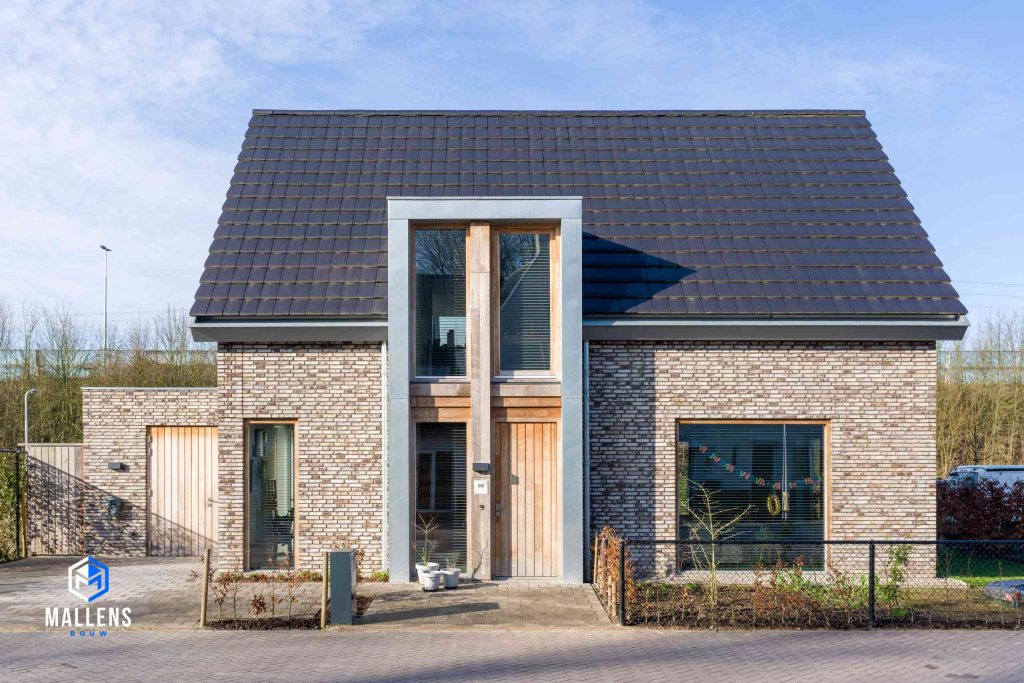 De voorkant van de nieuwbouwwoning in Berkel-Enschot. De woning heeft verschillend gekleurde stenen. De voordeur zit verwerkt in een risaliet.