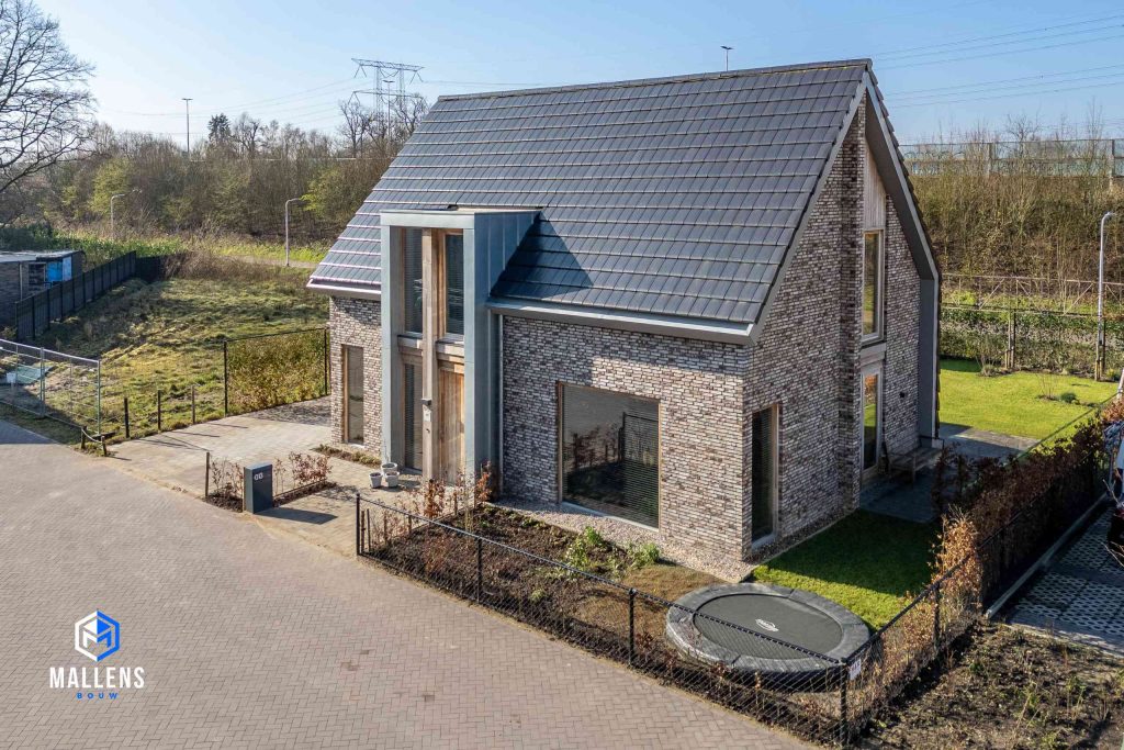 Het huis vanuit de lucht van schuin voren gezien. In de tuin staat een ingegraven trampoline.