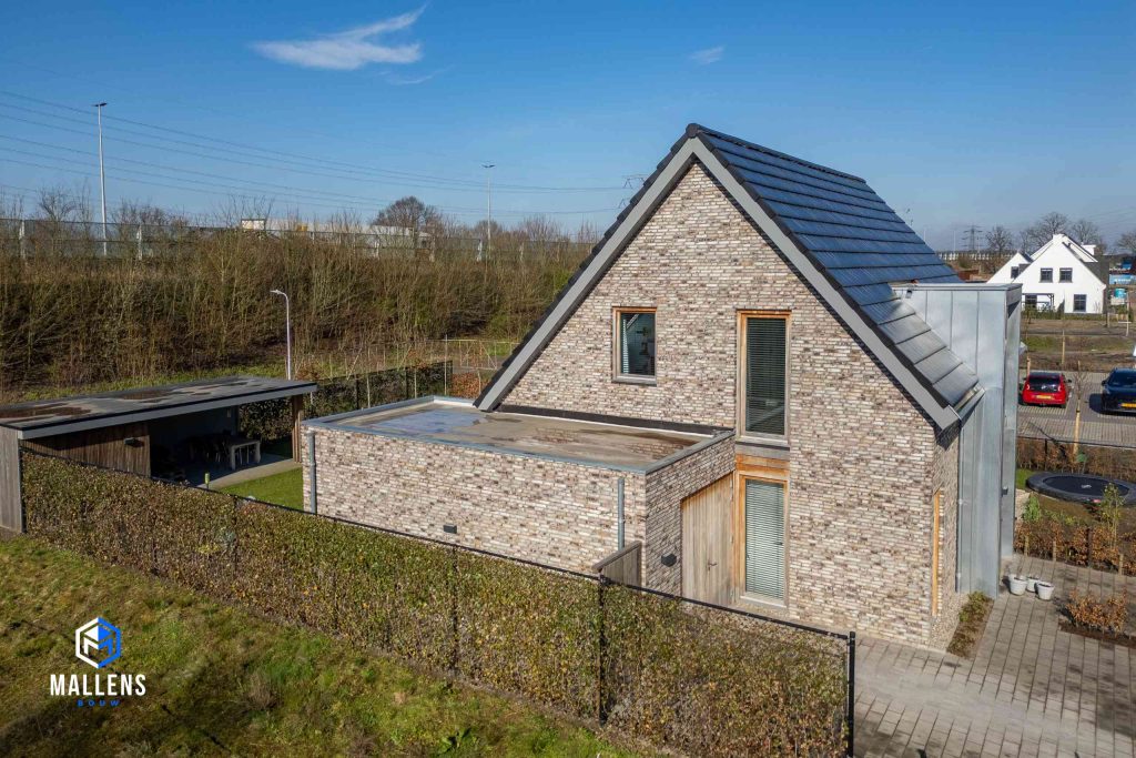 Het huis van de zijkant bezien, met zicht op de uitbouw met platte dak.