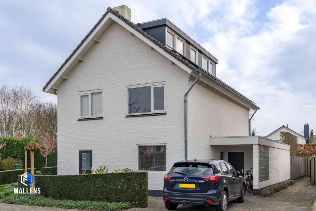 De woning van de zijkant gezien, met rechts een schuurtje. Op het dak zijn dakkapellen aanwezig.