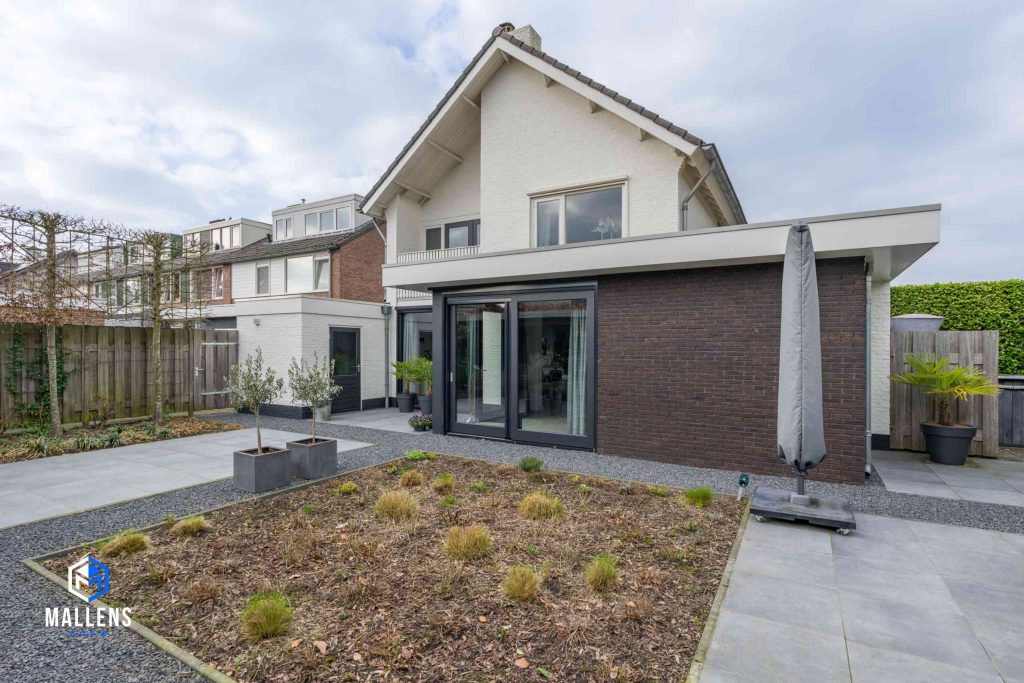 De woning met de uitbouw van schuin achter bekeken, met zicht op de achtertuin.