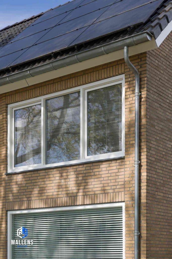 De bovenste ramen van de voorkant van het huis. Met zicht op de zonnepanelen van het dak.