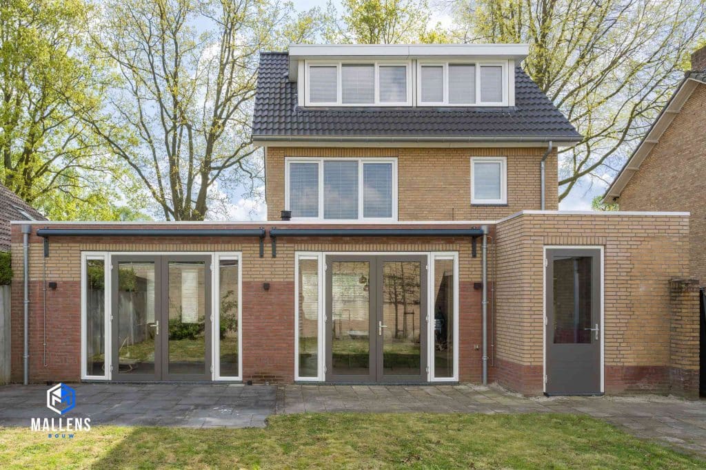 De achterkant van de woning, met 2 grote serredeuren. Op het dak is een grote dakkapel aanwezig.