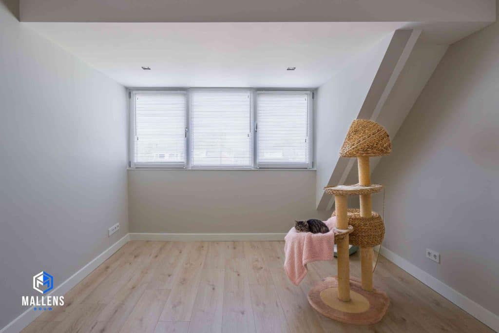 De zolderkamer die dankzij de dakkapel ruim en licht is. Er staat een kattenkrabpaal. In het mandje ligt een kat.