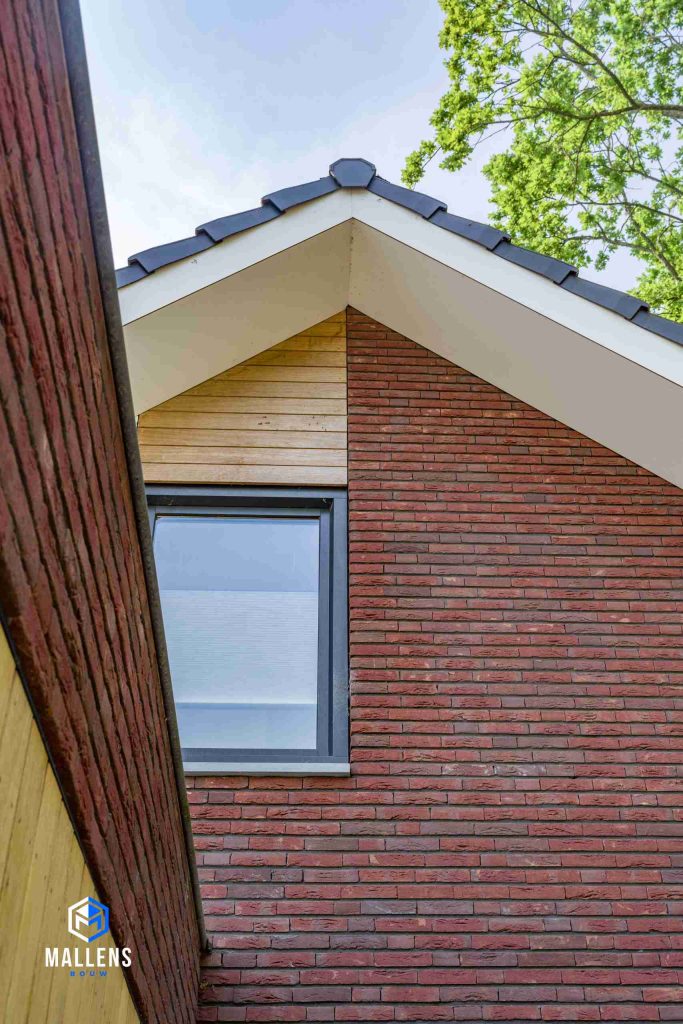 Close-up van de punt van het dak met ook hierboven het raam een de houten panelen