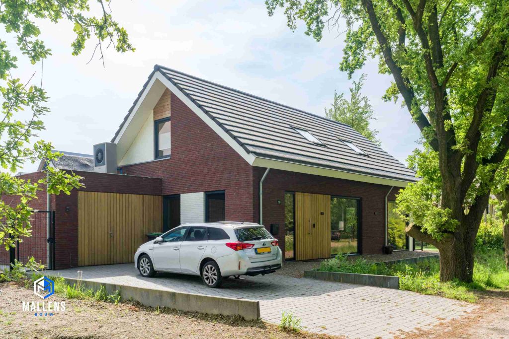 De nieuwbouwwoning in Heukelom van schuin van voren bekeken. De vrijstaande woning heeft een grote garage en grote houten voordeur.