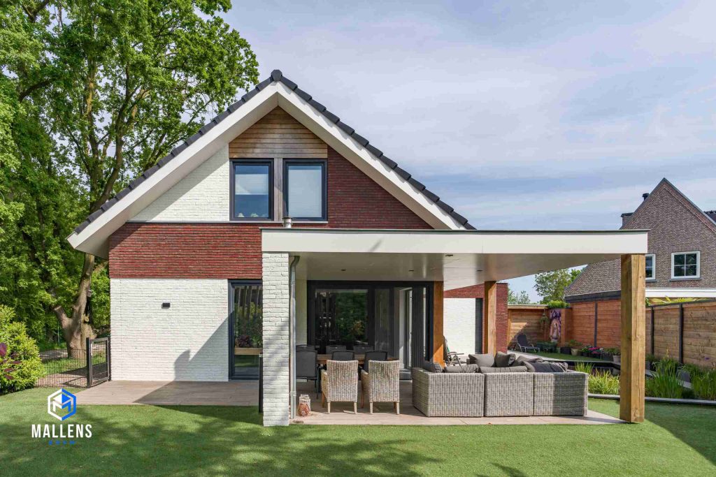 De achterzijde van de woning met zicht op de veranda. Boven de ramen zitten houten panelen.