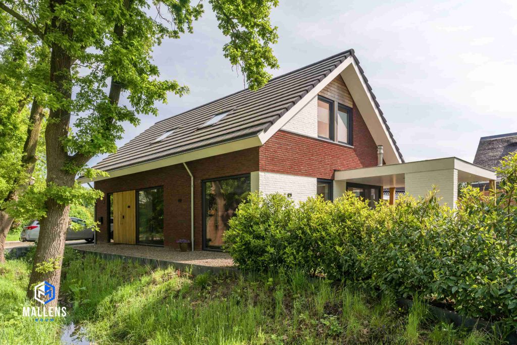 De woning van de andere kant bekeken. De woning heeft aan deze zijkant een combinatie tussen witte en rode bakstenen.